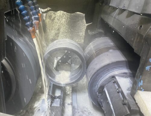 Metal cylinder being worked on with a double-grinding process with coolant, in SC Industries.