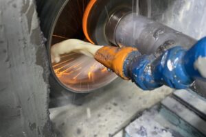 Intense close-up of metal grinding with sparks and coolant on a cylindrical part in SC Industries' Houston facility. Intense close-up of metal grinding with sparks and coolant on a cylindrical part in SC Industries' Houston facility.
